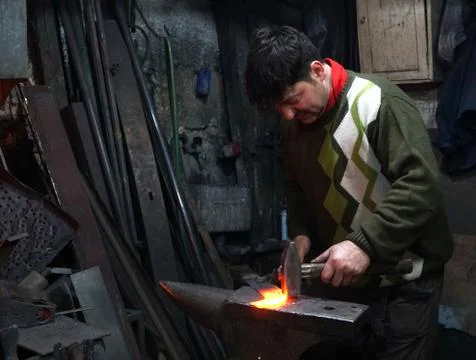 Blacksmith working in workshop Photos