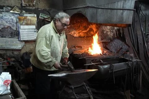 Blacksmith working in workshop Photos