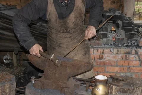 Blacksmith works in the forge with a hammer Stock Photos