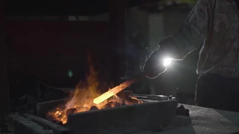 A blacksmith works with metal in a forge. Man prepares iron Stock Footage 298870945