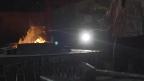 A blacksmith works with metal in a forge. Man prepares iron Stock Footage 298871007