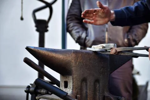 A blacksmith works with tools on an anvil. Forging a metal on an anvil. Stock Photos