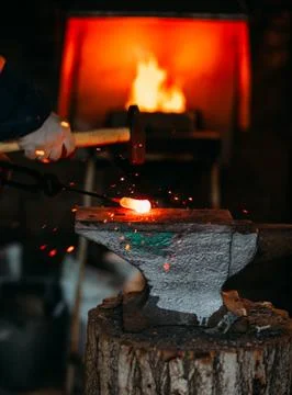 Blacksmith workshop. The blacksmith works on the anvil with a hot metal billet Stock Photos