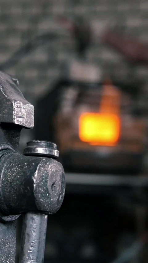 Blacksmith in workshop makes iron tools - kindle blast furnace, de-focused Stock Footage 332614458