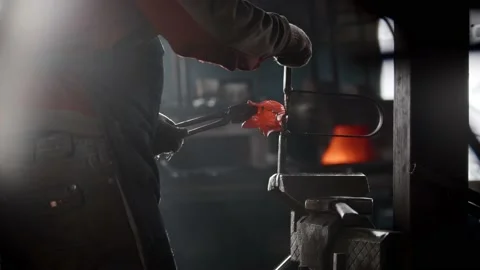 Blacksmith workshop - a man puts heated metal detail in the pressing retainer Stock Footage 180498154