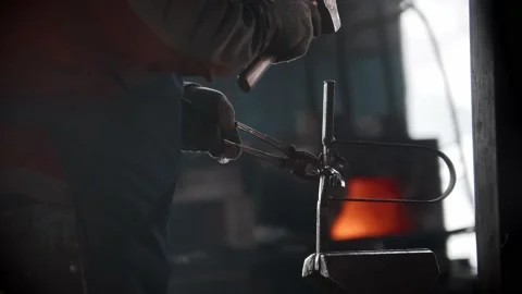 Blacksmith workshop - a man puts metal detail in the pressing retainer and hits Stock Footage 180499991