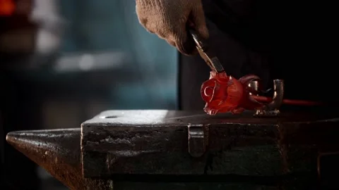 Blacksmith workshop - a man shaping rose leaves out of heated metal using Stock Footage 180503737
