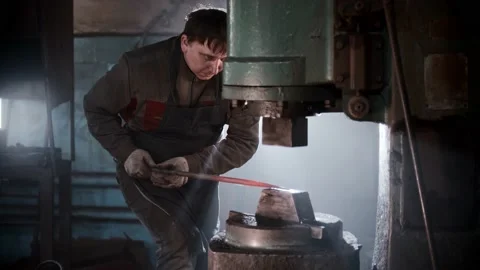 Blacksmith workshop - a man working with heated metal using automatic pressing Stock Footage 180503915