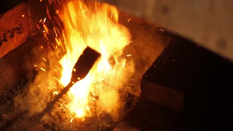 Blacksmithing forge. Using blower and rake to increase heat in hearth fire. Stock Footage 219957074