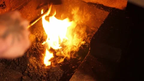 Blacksmithing forge. Using a rake to pull coal and charcoal into the fire. Stock Footage 219957050