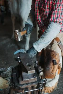 Blacksmith's hands working on an iron horseshoe with hammer Stock Photos