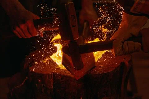 Blacksmiths hit molten metal with hammers close up Stock Photos