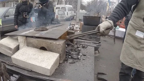 Blacksmiths by Tongs Move Workpiece in Small Blast Furnaces in Square Stock Footage 74793591