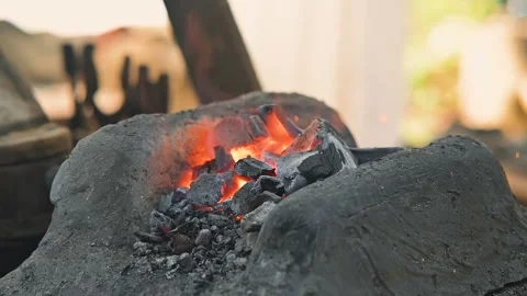 Blacksmiths work with a forge, heating coals to shape iron into tools. The 库存影片 345033569