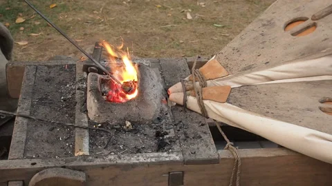 Blacksmiths working old fashioned bellows at the forge. The blacksmith holds the Stock Footage 103549299