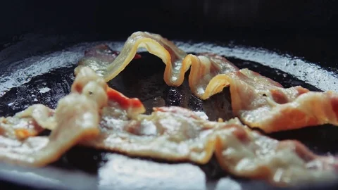 Blade corrects a slice of bacon on the surface of the pan. Stock Footage 77613854
