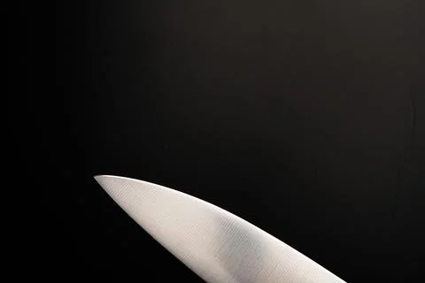 The blade of a large knife on a black background. Dimmed lights. Foto stock