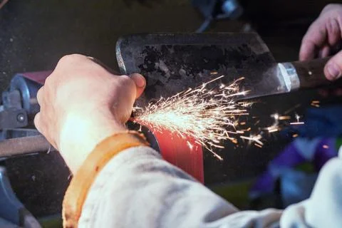 Blade sharpening creating on a belt grinder process. Knife making master hand Stock Photos