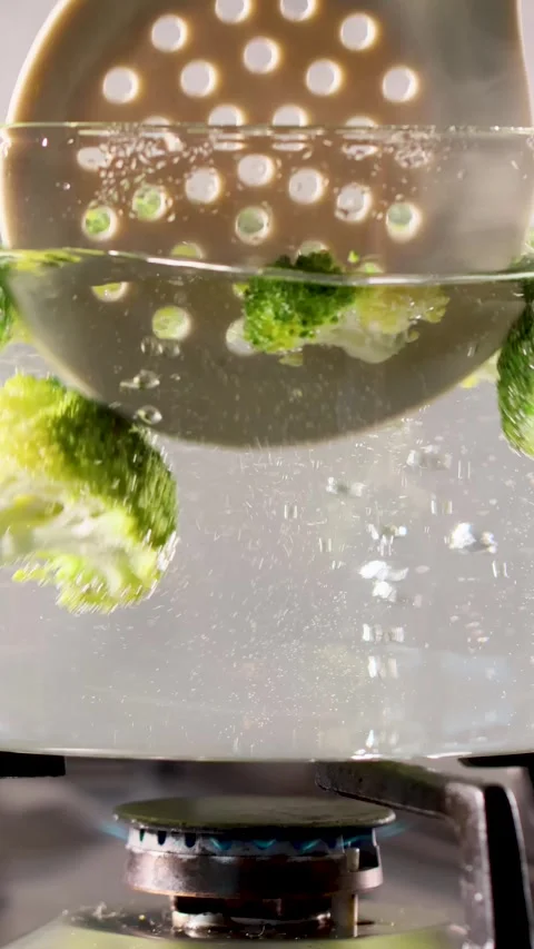 Blanching broccoli florets in boiling water close up kitchen scene Stock Footage 345426498
