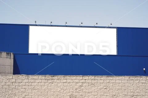 Blank advertising billboard in metallic frame with spotlight on blue building Stock Photos