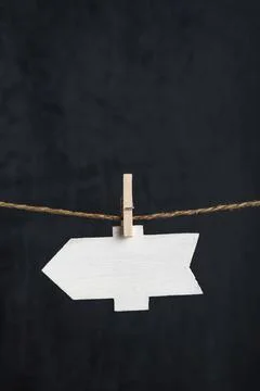 Blank arrow pointer hang with clothespins on rope on black background. Small  Stock Photos