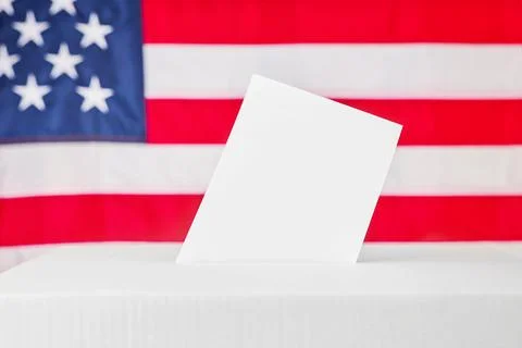 Blank ballot standing in a voting box before an American flag Stock Photos