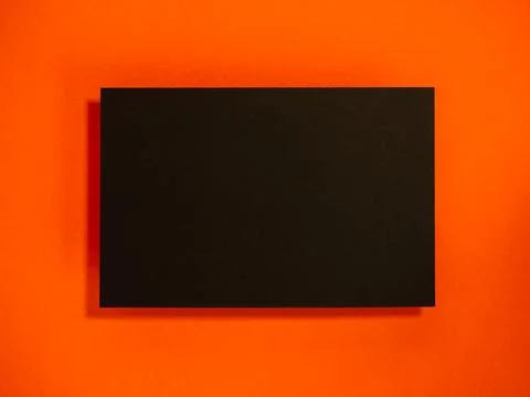 Blank black card displayed on a horizontal vibrant orange background with s.. Stock Photos