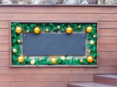 Blank black plaque in a frame with New Year's decor in the form of fir branches Stock Photos
