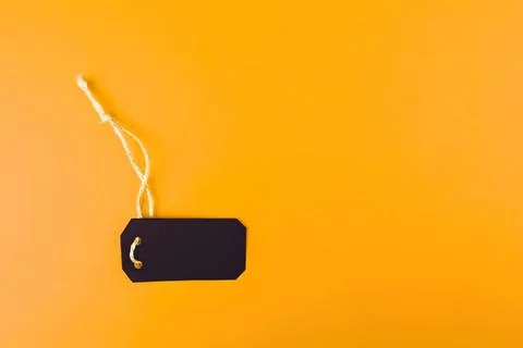 Blank black price tag with string on orange background Stock Photos