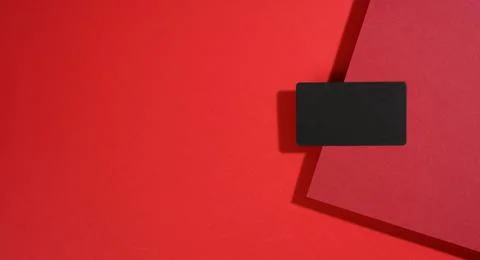 Blank black rectangular business card lies on a modern red background with re Stock Photos