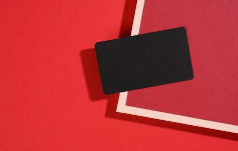 Blank black rectangular business card lies on a modern red background with re Stock Photos