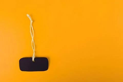Blank blackboard hanging on a string against orange background Stock Photos