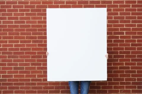 Blank board held ready for text in front of brick wall Stock Photos