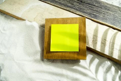 Blank bright green sticky note on a wooden block, set against white sand an.. Stock Photos