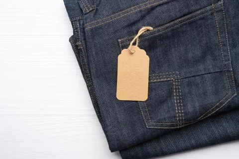 Blank brown rectangular tag tied in the back pocket of blue folded jeans 스톡 사진