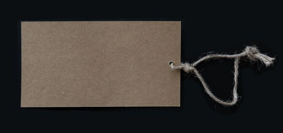Blank brown tag with rustic thread string isolated on black background. Stock Photos