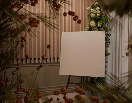 Blank canvas on easel, surrounded by decorative plants and warm tones Stock Photos