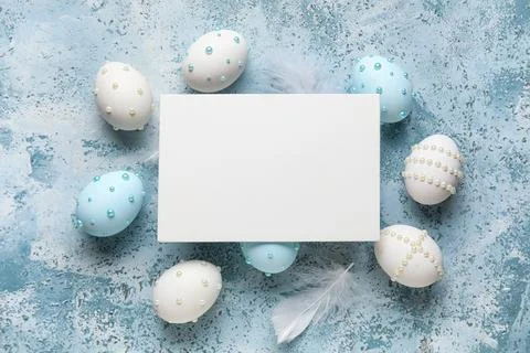 Blank card and Easter eggs decorated with pearls on blue grunge background Stock Photos
