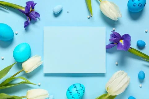 Blank card with Easter eggs, flowers and beads on blue background Stock Photos
