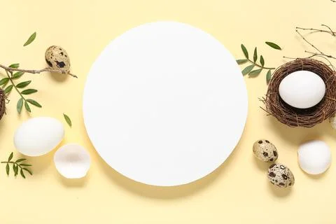 Blank card with Easter eggs, leaves and tree branches on beige background Stock Photos
