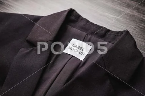 Blank clothing tag on the texture of a black blazer. Label with empty space f PSD Template