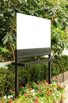 A blank digital display stands in front of colorful flowers in a garden. The  Stock Photos