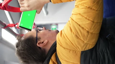 Blank digital phone with chroma key green screen in hand of guy standing indoors Stock Footage 169454580