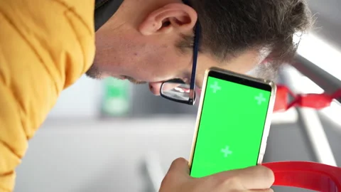 Blank digital phone with chroma key green screen in hand of guy standing indoors Stock Footage 169746229