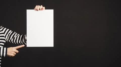 Blank empty A4 paper board and pointing in woman's hands on black background. Stock Photos