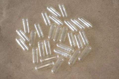 Blank empty capsule on a beige old paper background. Stock Photos