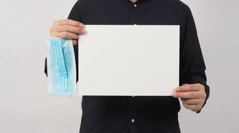 Blank empty paper in man hand wirh face mask and wear navy blue shirt on whit Stock Photos