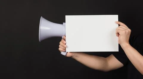 Blank empty paper in man's hand with megaphone on black background. Stock Photos