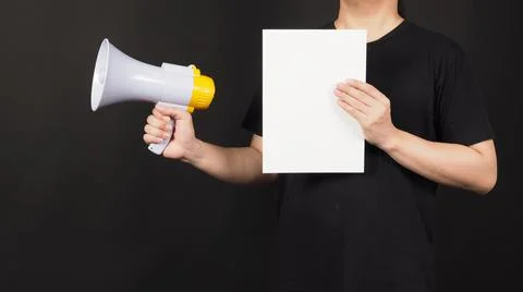 Blank empty paper in man's hand with megaphone on black background. Stock Photos