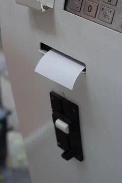 Blank empty white check is sticking out gray ATM machine with keyboard Stock Photos